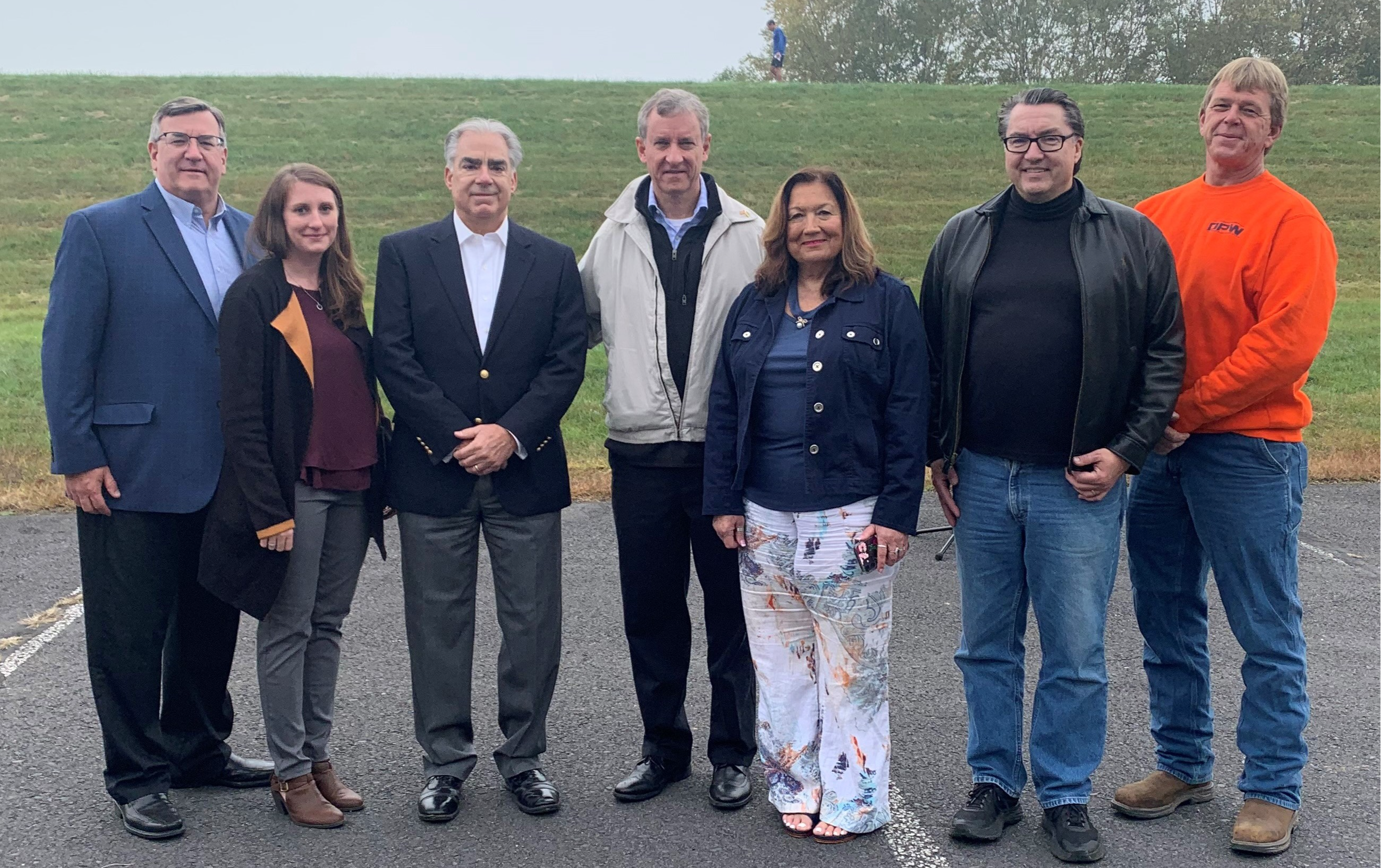 A group of people stand with Congressman Cartwright in the middle in front of a levee