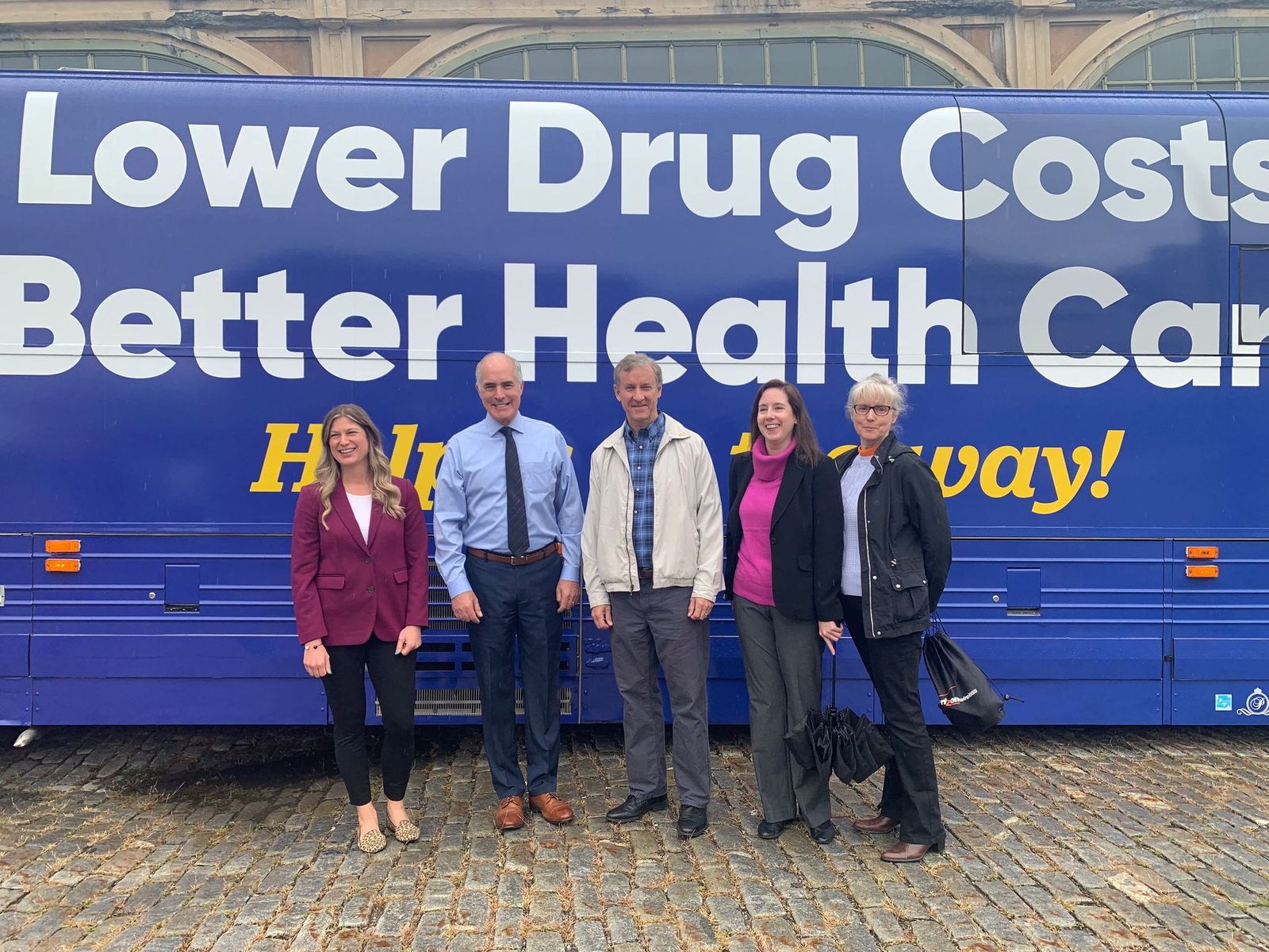 Rep Cartwright standing in front of bus reading: Lower drug costs, better health care